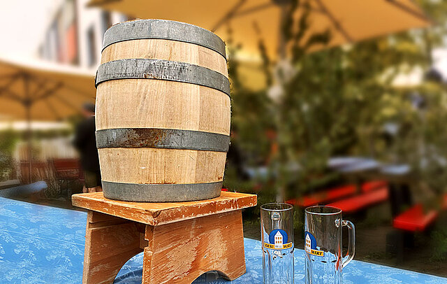 Holzfass mit zwei Bierkrügen daneben Holzfass mit zwei Bierkrügen daneben