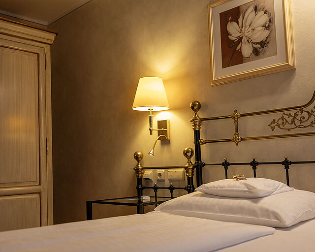 [Translate to English:] Elegantes Bettgestell mit Lampe daneben