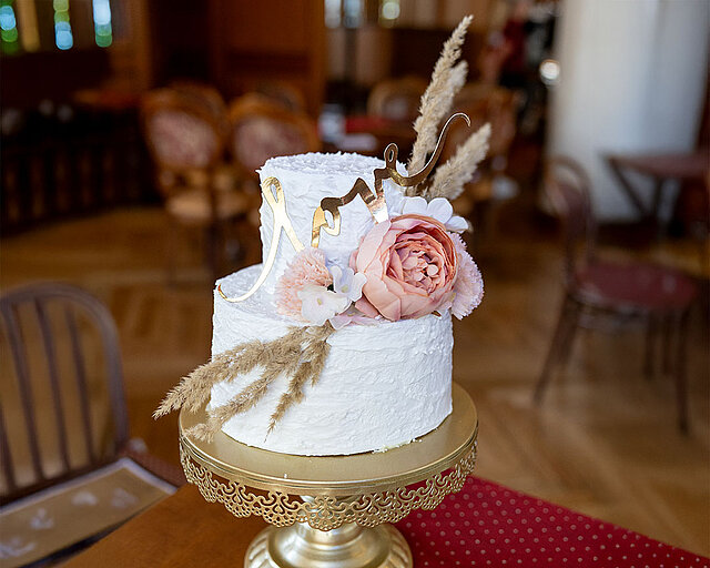 White cake with a golden lettering and flowers. White cake with a golden lettering and flowers.